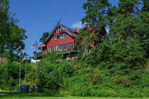 Curonian flags in front of a traditional wooden house