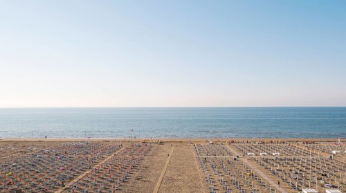 View of a beach with sunshades and sun beds at sunrise