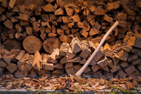 Axe and piles of stacked firewood in an outdoor shed
