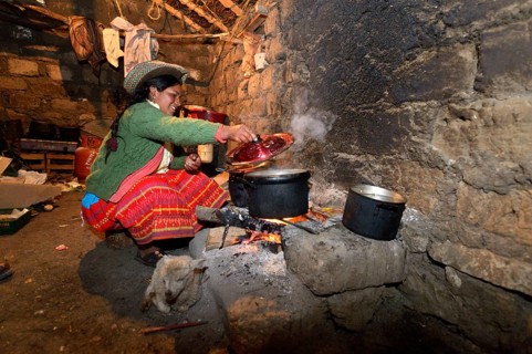 Young woman cooking on an open fire in her traditional kitchen