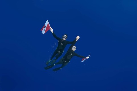 Freedivers holding a diver down flag