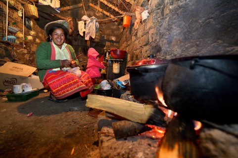 Young woman cooking on an open fire in her traditional kitchen
