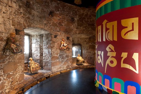 Room with a Tibetan prayer wheel and Buddha statues