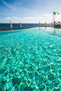 Swimming pool and the Mediterranean with the flag of Italy