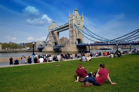 Tourists relaxing in Potters Fields Park in front of Tower Bridge