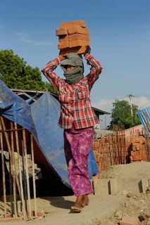 Female construction worker carry bricks on their heads