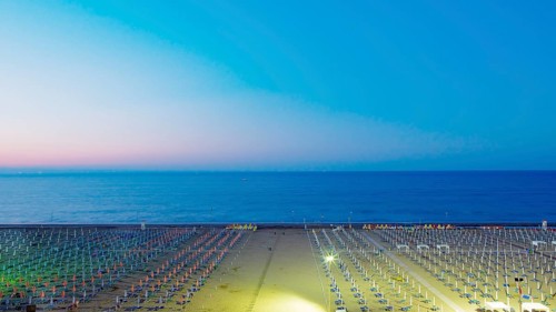 View of a beach with sunshades and sun beds at twilight