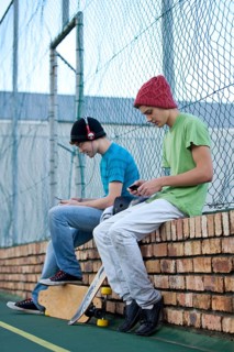 Two teenage boys sitting on a brick wall