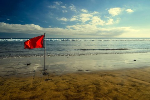 Red bathing prohibition flag standing on a beach