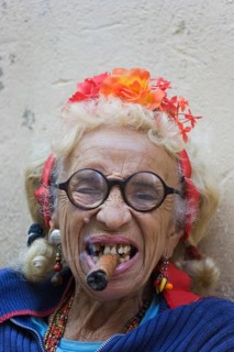 Old woman wearing coulorful clothes posing with a cigar