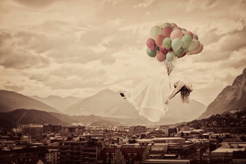 Bride floating on balloons over Innsbruck