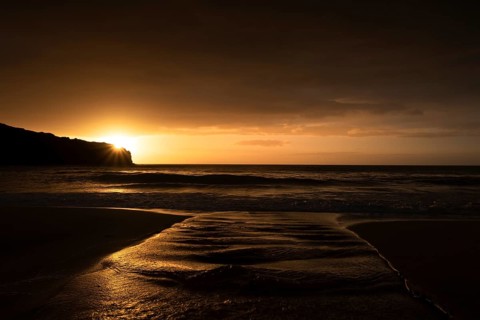 A brook flows over the sandy beach into the sea