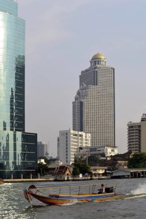Long-tail boat on the Chao Phraya River with the State Tower at back