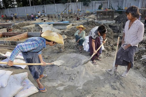 Children and teenagers mix concrete on a high rise construction site