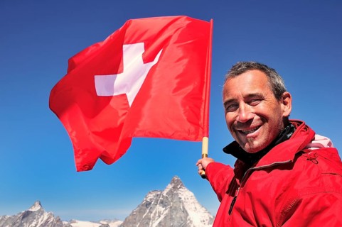 Tourist holding a Swiss flag over the Matterhorn