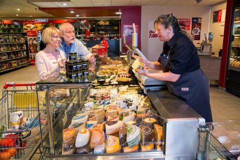 Shop assistant serving a senior couple at the cheese counter