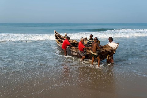 Fishermen pushing a boat onto the beach