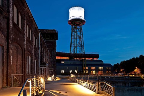 Jahrhunderthalle or Centennial Hall with a water tower at dusk