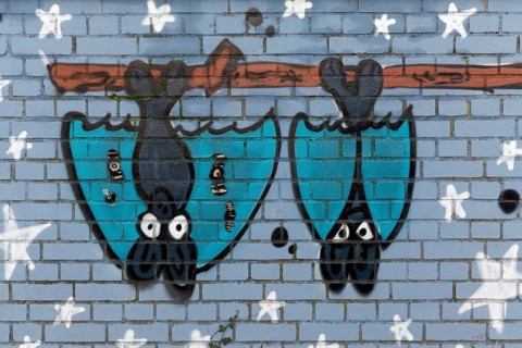 Two bat figures hanging upside down on a pole
