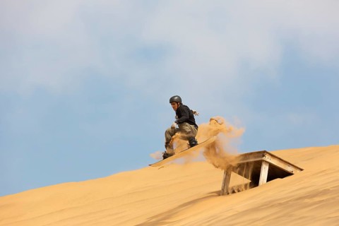 Sand boarding in the dunes of the Namib Desert
