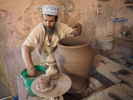 Potter makes pottery with potter's wheel a clay jug