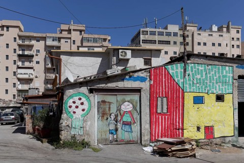 Brightly painted huts in front of modern residential buildings