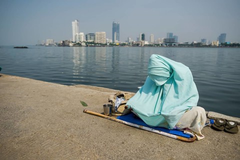 A Muslim woman wearing a burka is begging for money on the walkway