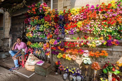 A street vendor is selling colorful artificial flowers