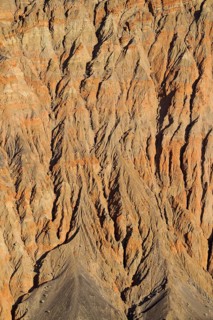 Exposed fissured bedrock of orange-colored conglomerate on the crater wall of Ubehebe Crater