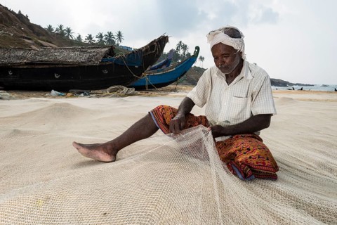 Fisherman repairing fishing nets on the beach