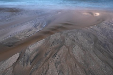Water flows into the sea at the sandy beach
