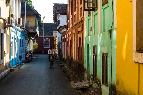 A small lane with colourful houses and a cyclist