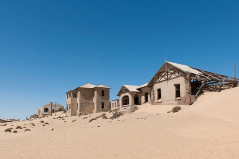 Houses of a former diamond miners settlement that is slowly covered by the sand of the Namib Desert