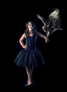 Girl wearing a black ballet dress with a bird of prey on her arm