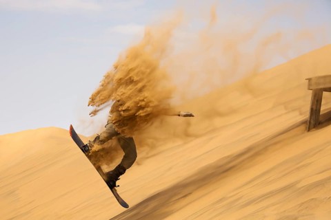 Sand boarding in the dunes of the Namib Desert