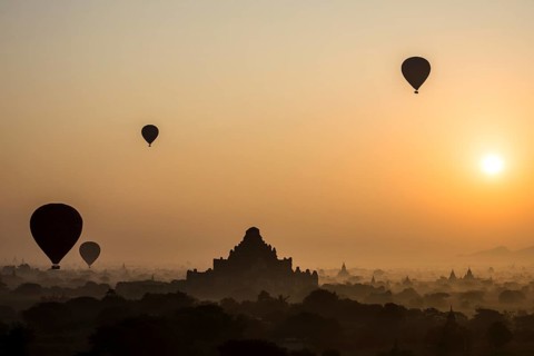 Hot air balloons over the landscape in the early morning fog