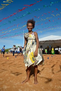 Girl presenting a dress made of recycled newspapers at a fashion show of a social project