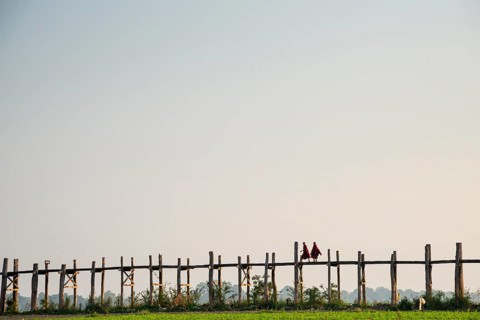 Monks walking on a teak bridge
