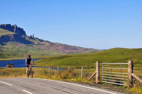 Cyclist on a road at The Storr with the The Old Man of Storr pinnacle