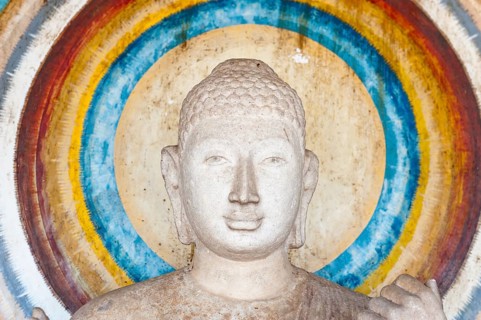 Head of a Buddha figure surrounded by a nimbus in rainbow colors