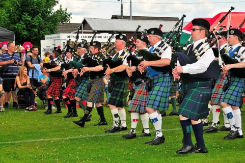 Pipe band marching in unison on the sports ground at the Highland Games