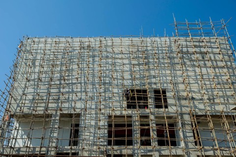 A construction site of a new concrete building with bamboo scaffolding attached