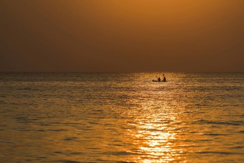Two kayakers in the open sea at sunset
