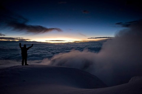 Mountain climber on the summit of Cotopaxi Volcano at sunrise