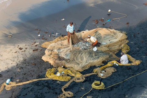 Fishermen inspecting fishing nets on the beach