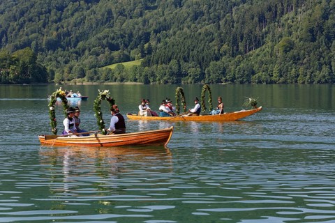 Locals wearing traditional costumes in decorated wooden Platte boats