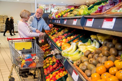 Senior couple shopping with a shopping trolley in the fruit and vegetables department of a supermarket