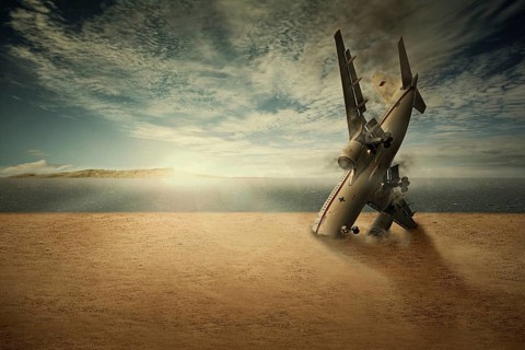 A crashed plane with the nose stuck in the sand on a beach