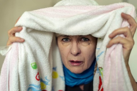 Senior woman with a cold inhaling under a towel
