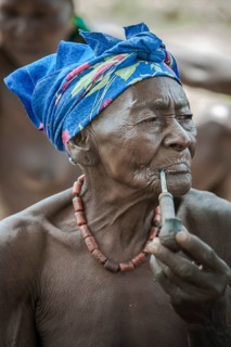 An elderly woman from the Koma people smoking a pipe